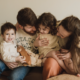 Two parents and two young children cuddle together on a couch.