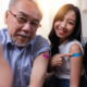 Two people show off their colourful bandaids on their upper arms.