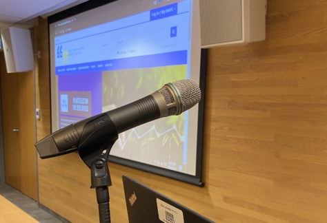 A microphone, laptop and projector screen inside the Auditorium at New Westminster Public Library's Main Branch.