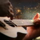 Sparkly lights hover over a ukulele being played.