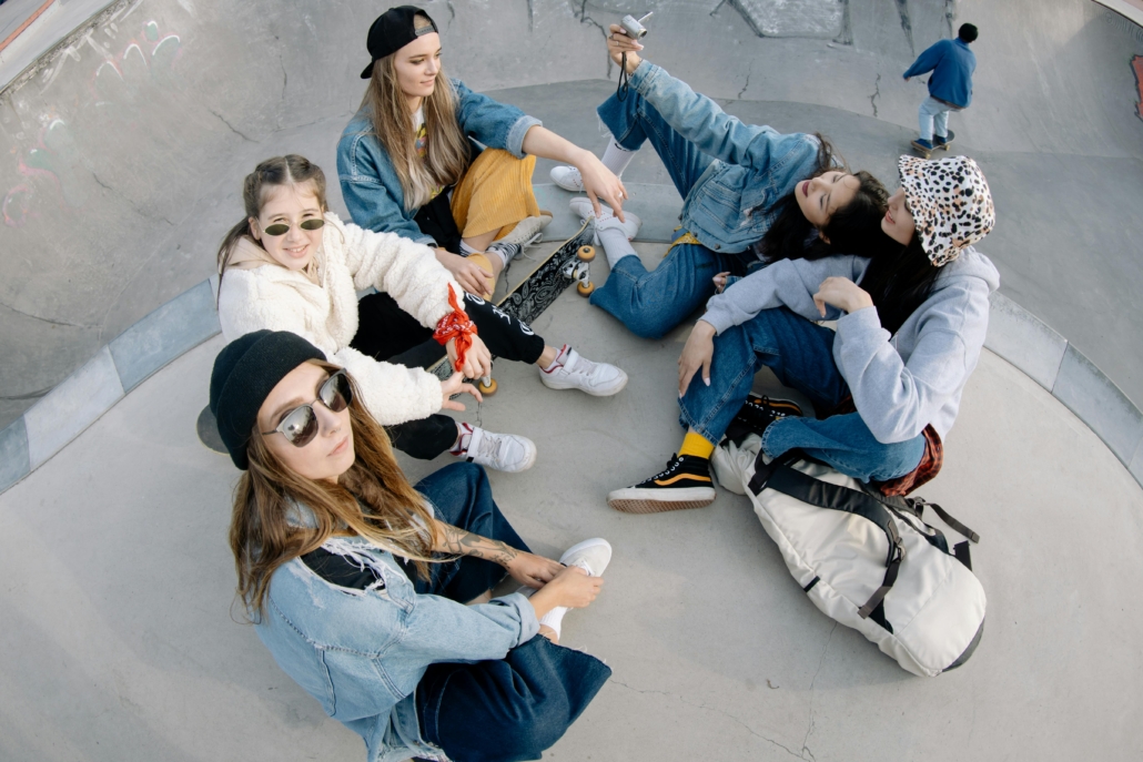 Five teens lounge around at a skate park.