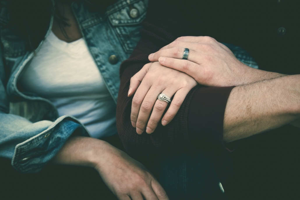 Closeup of two people with the focus on their interlinked arms and one's hand resting on top of the other's hand.