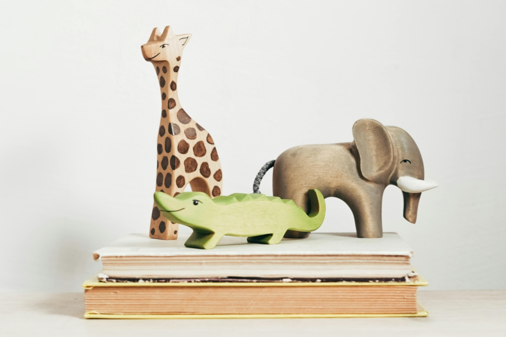 Trio of toy animals sit atop a short stack of books.