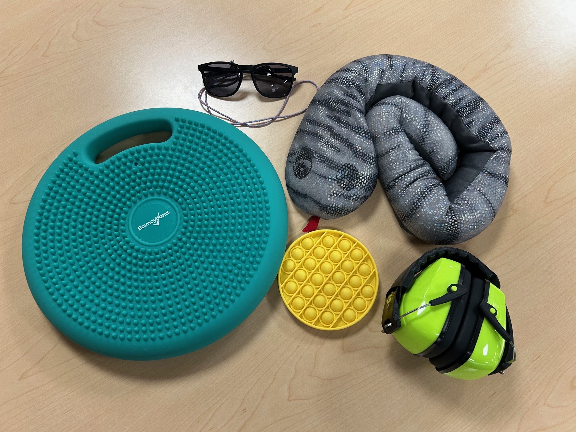 Sensory support items including a a wobble cushion, sunglasses, and noise-reducing headphones.