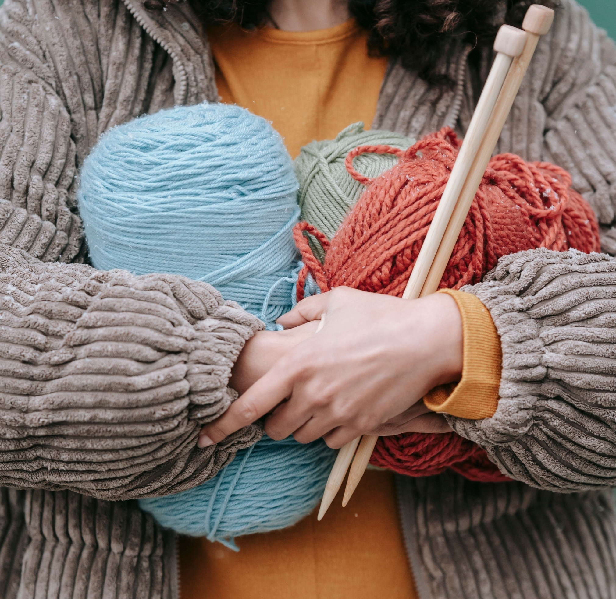 Person holding 3 large bundles of yarn in front of them.